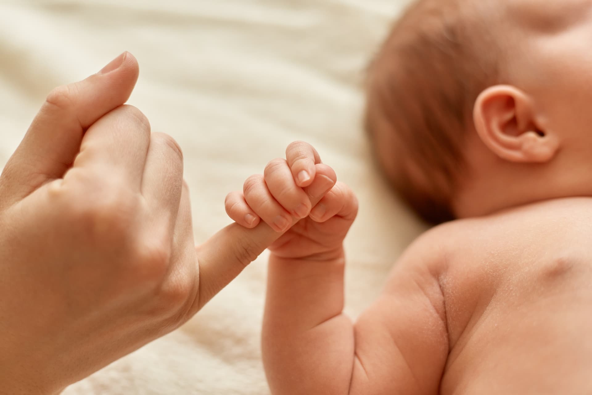 Moeder houdt hand van baby vast op lichte achtergrond